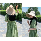 Beige UPF 50 sun protection hat paired with a green checkered dress in a sunny outdoor setting