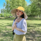 Woman wearing a stylish UPF 50 sun protection hat outdoors in a shaded park area