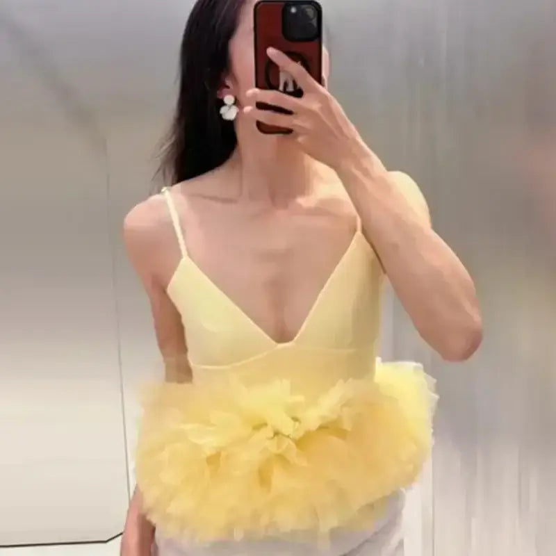 Yellow puffy sleeveless summer top with floral tulle detail worn by woman taking mirror selfie