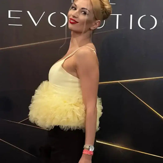 Woman wearing a yellow puffy sleeveless summer top with a tulle skirt detail by The Lady's Haven Boutique