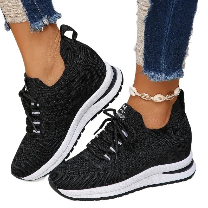 Black lightweight walking shoes with white sole and knit upper worn with jeans and ankle bracelet