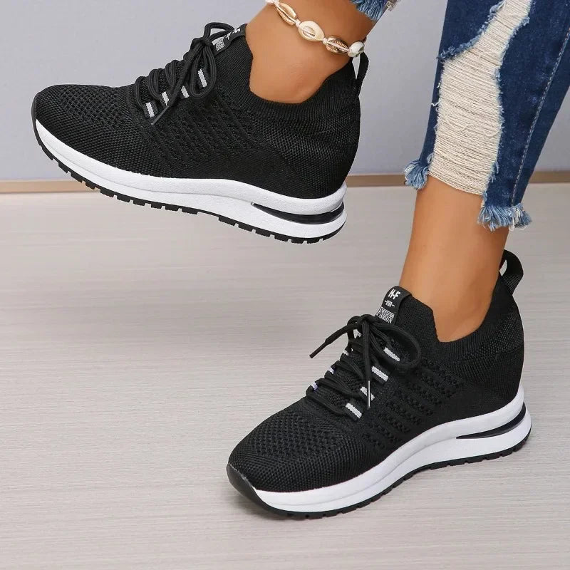 Black lightweight walking shoes with white soles worn with distressed blue jeans