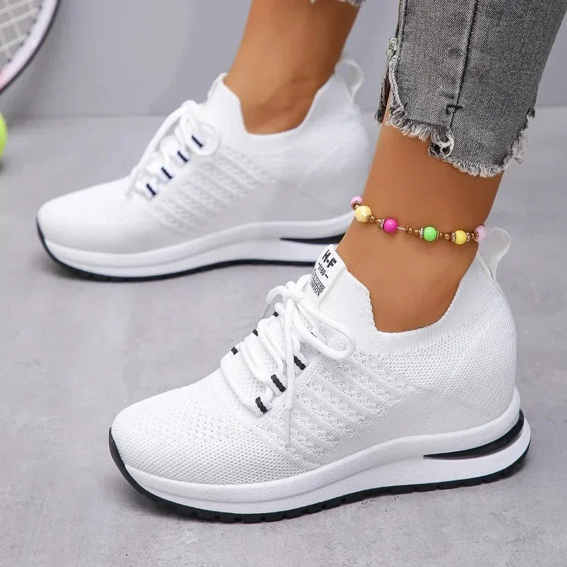 White lightweight walking shoes with knit upper and cushioned sole worn with gray frayed jeans
