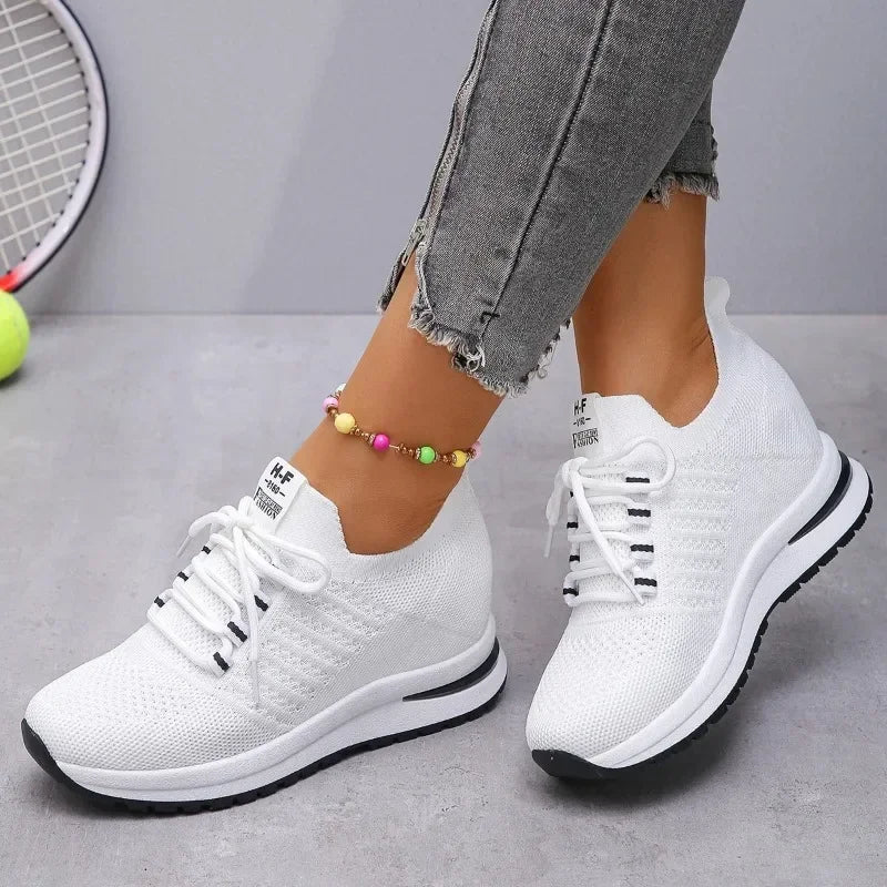 White lightweight walking shoes with knit fabric and black sole worn with gray frayed jeans