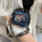 Luxury embroidered crossbody bag featuring a colorful elephant design and adjustable strap