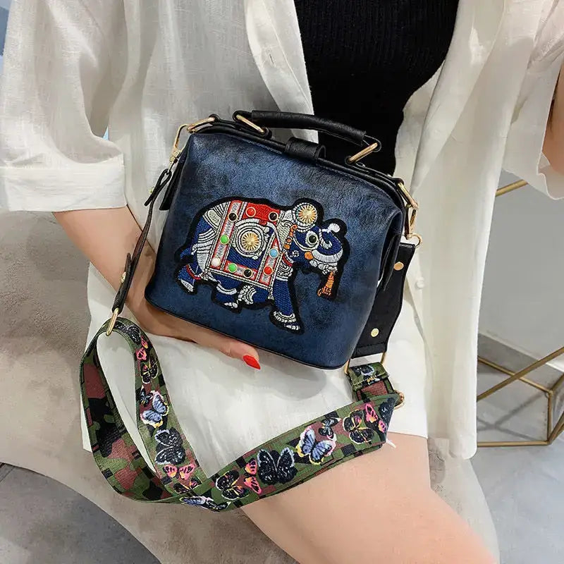 Luxury embroidered crossbody bag featuring a colorful elephant design and adjustable strap