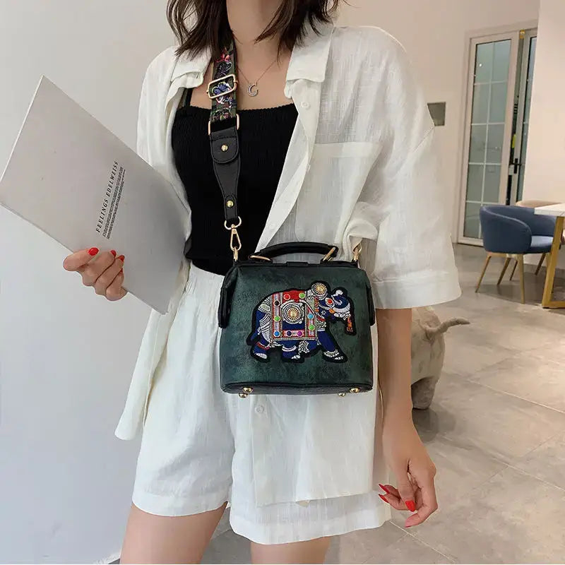 Luxury embroidered crossbody bag in black with colorful elephant design and adjustable strap