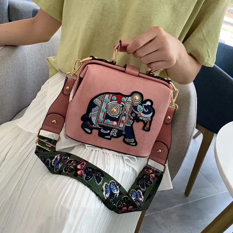 Luxury embroidered crossbody bag featuring an elephant design and colorful strap for stylish convenience