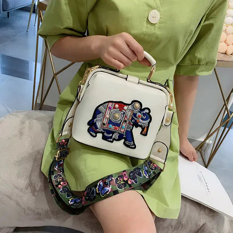 Elegant lady holding a luxury embroidered crossbody bag with colorful elephant design