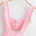 Close-up of a pink mini slip dress with wide straps hanging on a wooden hanger