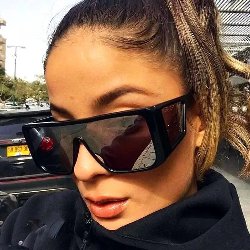 Stylish woman wearing oversize fashion sunglasses with bold frames and reflective lenses