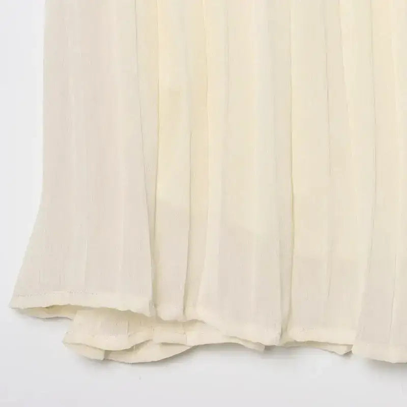 Close-up of cream-colored pleated chiffon midi skirt fabric texture and hem detail