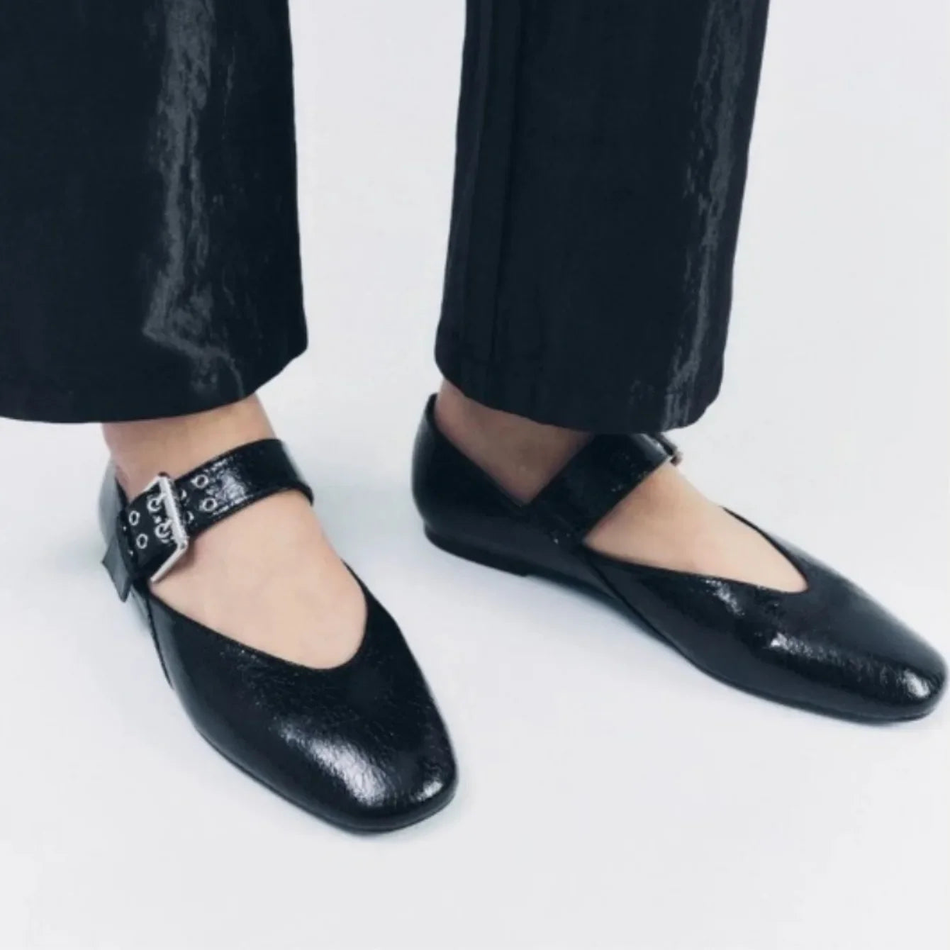 Black pointed toe flats with buckle strap worn with black pants for stylish comfort