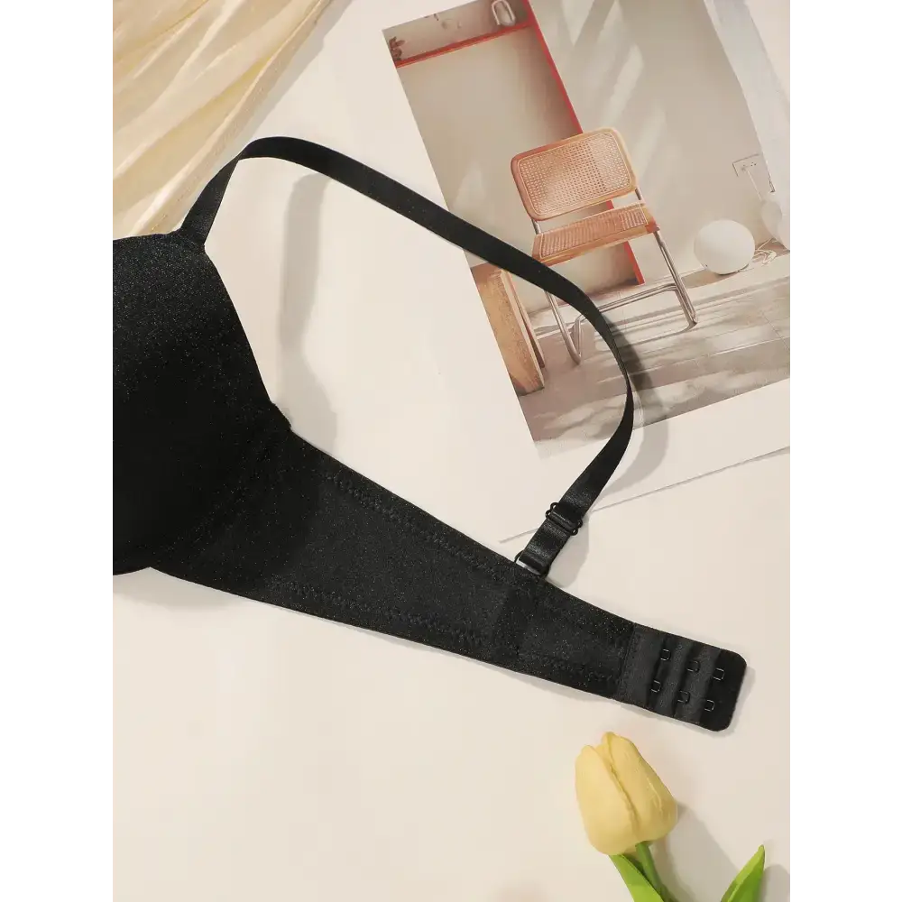 Black sequin lingerie bra with steel ring detail from The Lady's Haven Boutique displayed on white surface with a yellow tulip