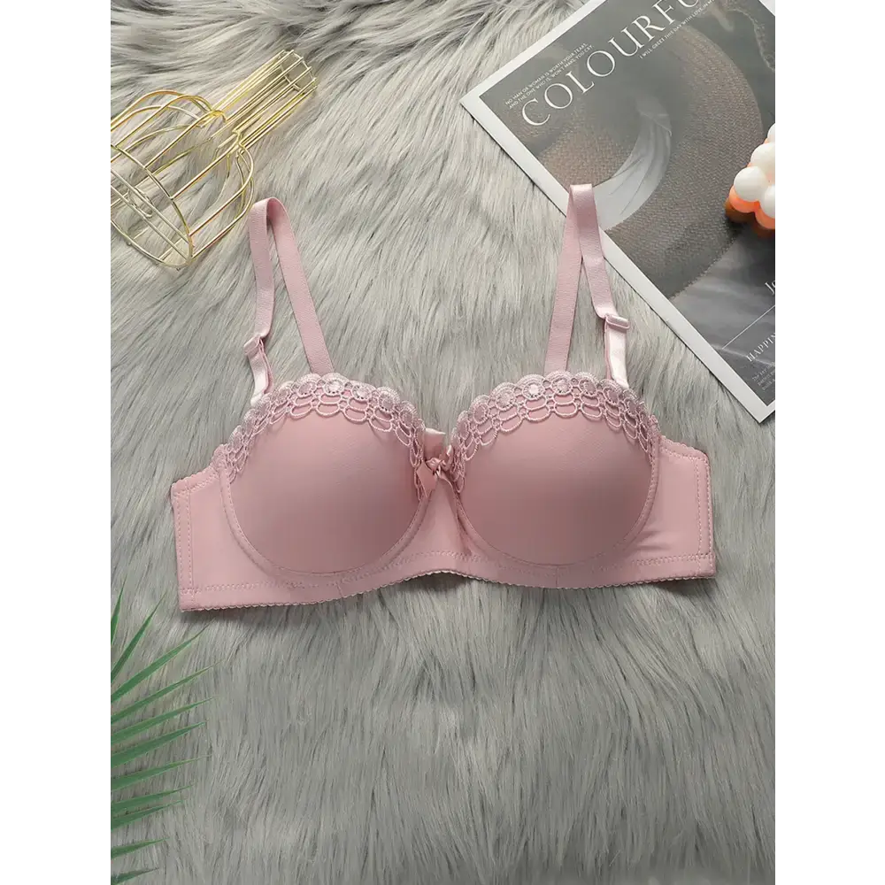 Pink sexy embroidered flower bra with adjustable straps laid on soft gray surface