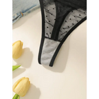 Black sexy embroidered lace lingerie set thong with polka dot mesh and solid trim laid on white surface with yellow tulips
