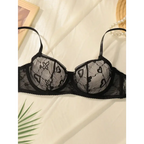 Black delicate sexy lace lingerie set bra with heart and floral patterns on white fabric background