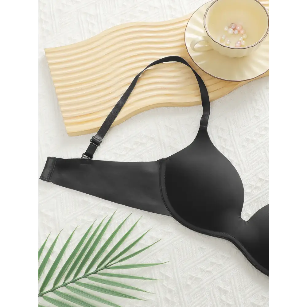 Sexy lingerie black bra from The Lady's Haven Boutique displayed on textured surface with plant and cup