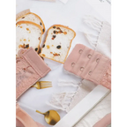 Pink sexy lingerie embroidered lace bra with hooks laid next to raisin bread slices on white fabric