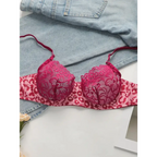 Sexy pink leopard print lingerie set bra with lace cups laid on denim fabric
