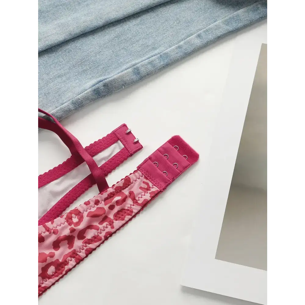 Close-up of sexy pink leopard print lingerie set strap and hook detail on white surface