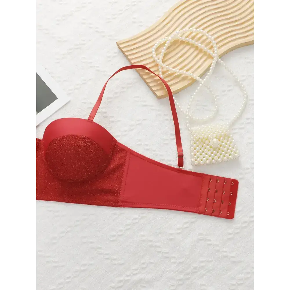 Sexy red bra and panty set with glittery cups and adjustable straps laid flat on white surface