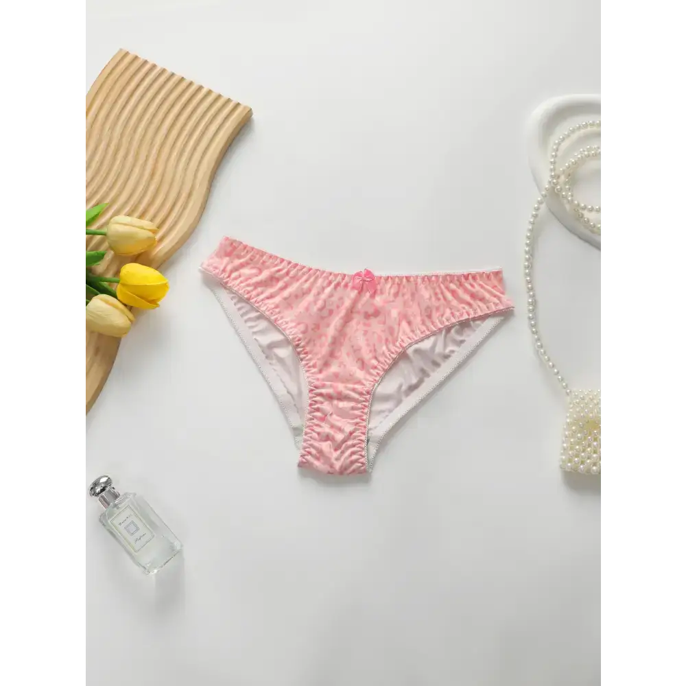 Pink panty from sexy underwire bra and panty set displayed on white surface with decorative flowers and pearl accessories
