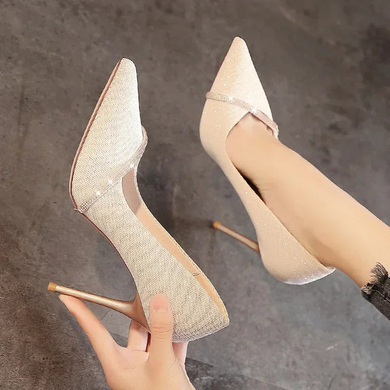 Elegant single strap stiletto heels in glittery beige worn on feet and held in hand