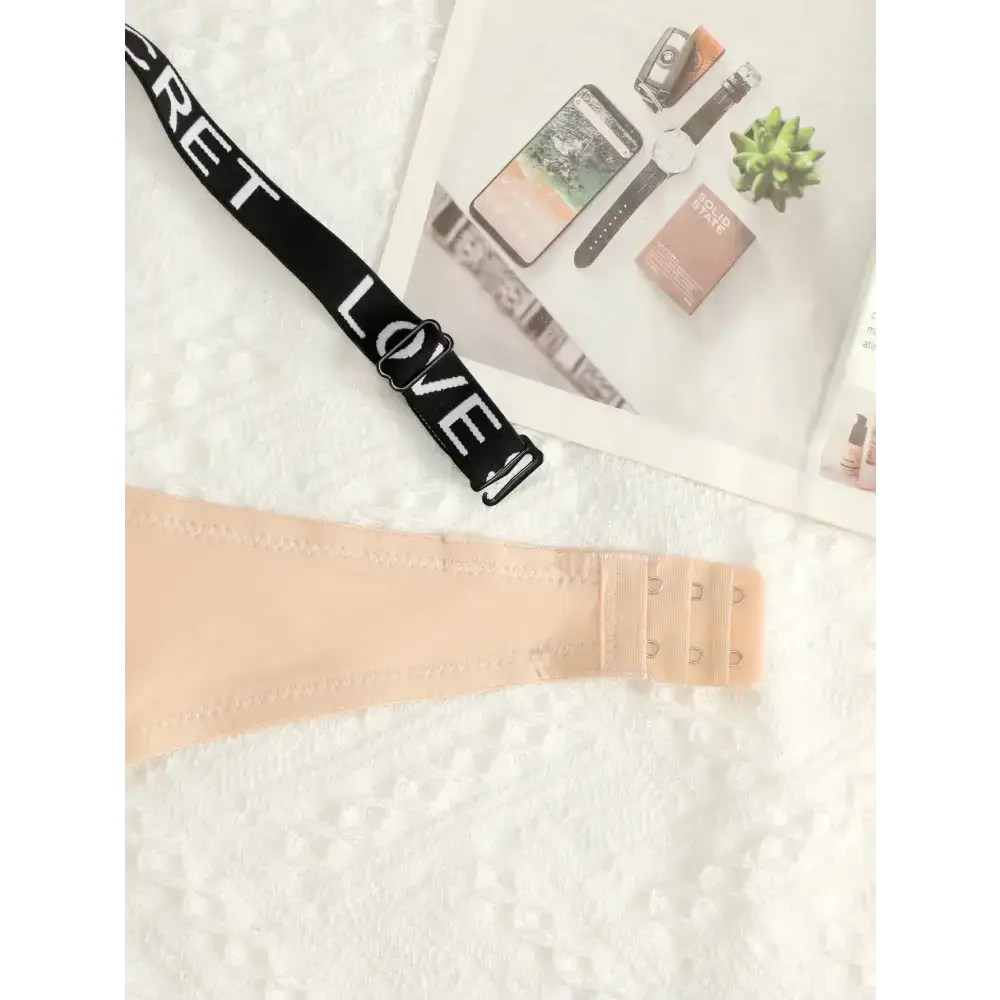 Beige small chest lifting underwear strap with black adjustable band featuring love text