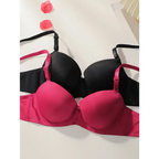 Solid color bra and panty set in black and pink laid flat with rose petals