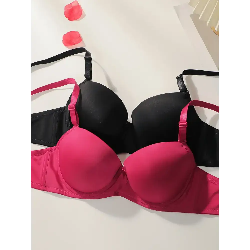 Solid color bra and panty set in black and pink laid flat with rose petals