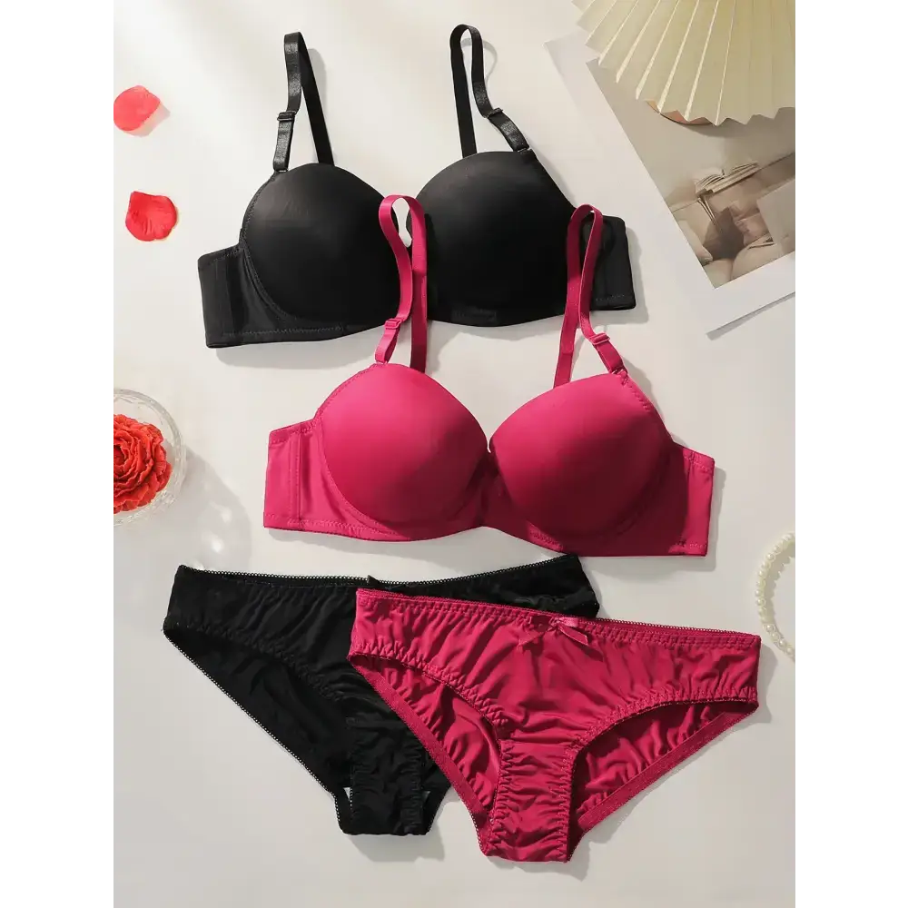 Black and pink solid color bra and panty set from The Lady's Haven Boutique laid out on a white surface