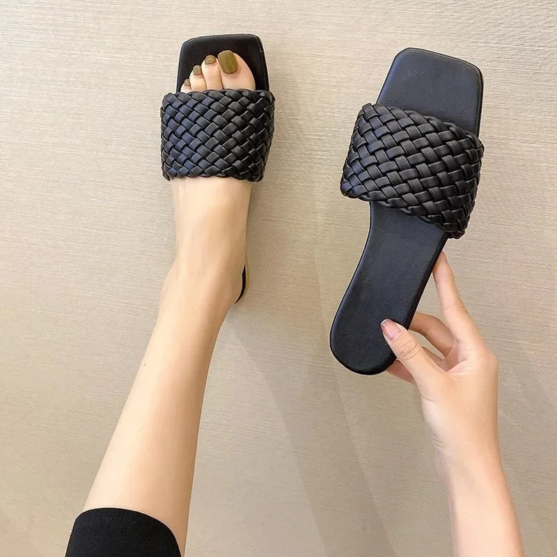 Black woven strap summer casual flip flops worn on foot and held in hand for stylish look