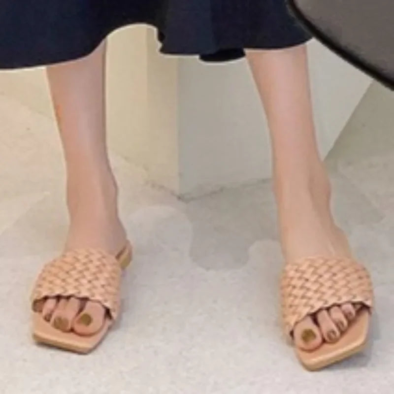 Beige woven summer casual flip flops worn with black skirt on light floor