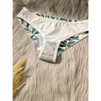 White bikini bottom with green summer leaf print lingerie set on a furry background