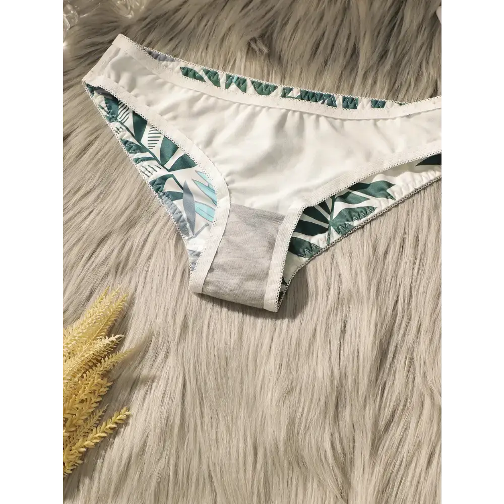 White bikini bottom with green summer leaf print lingerie set on a furry background