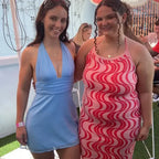 Woman wearing blue off shoulder halter mini dress standing next to woman in pink patterned dress