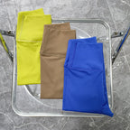 Stylish two piece workout clothing for women featuring bright yellow, tan, and blue leggings folded on a chair