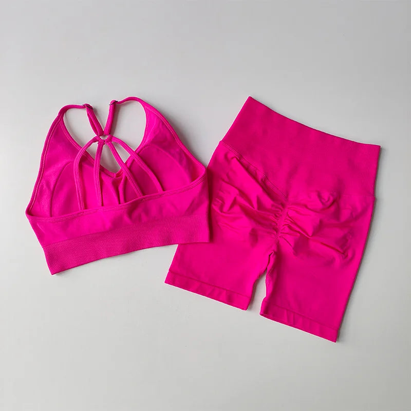 Bright pink two piece workout outfits featuring a stylish crisscross sports bra and matching high-waisted shorts