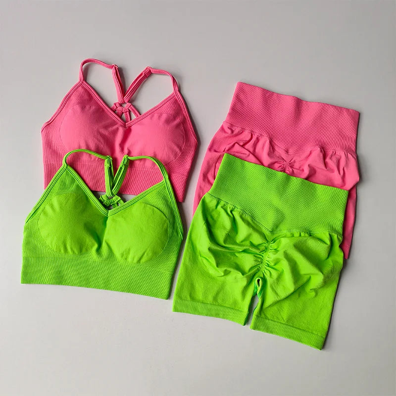 Vibrant pink and green two piece workout outfits featuring stylish crop tops and high-waisted shorts