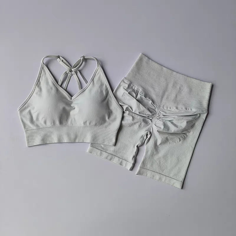 Stylish two piece workout outfits in light gray featuring a crisscross sports bra and high-waisted shorts