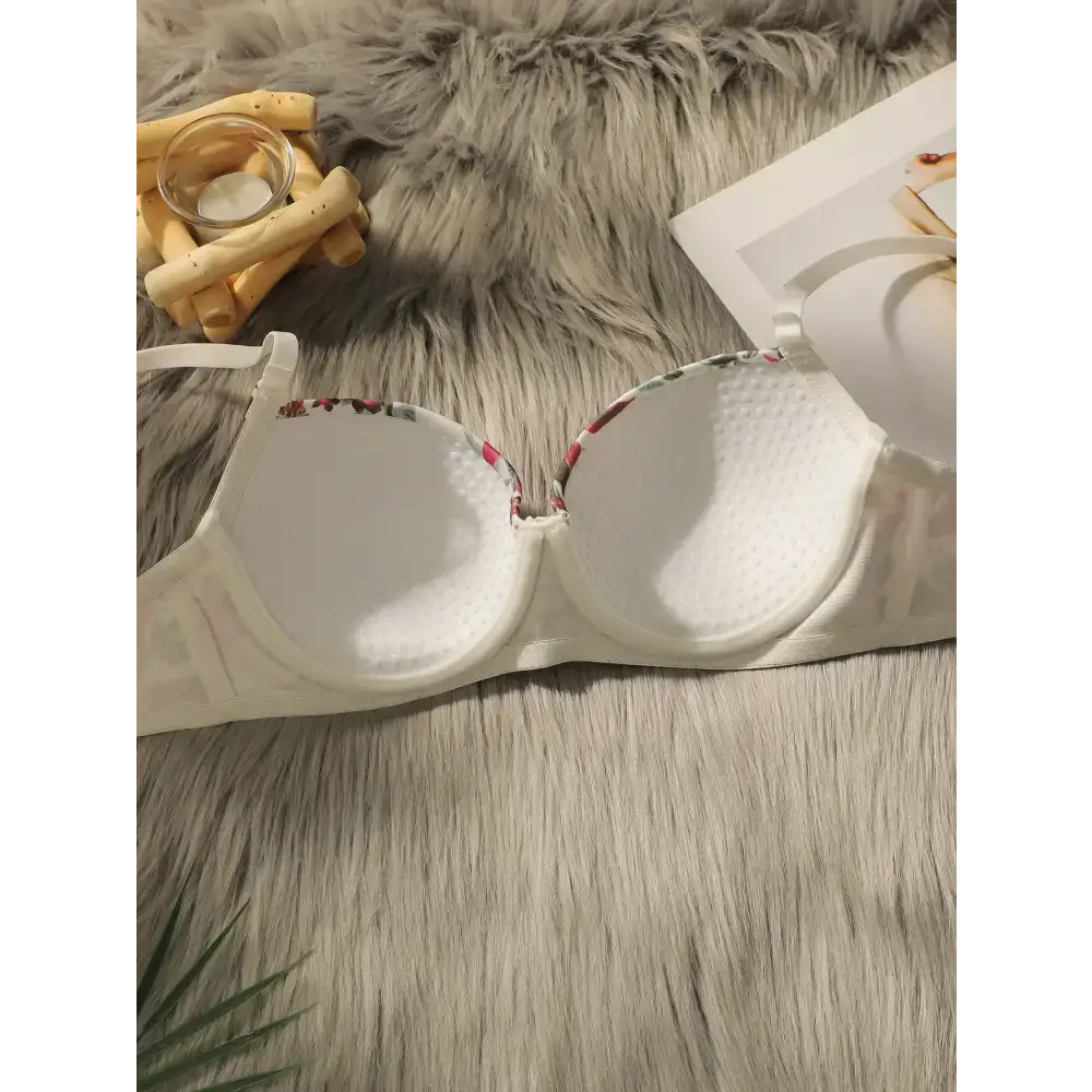 White close fitting floral bra and panty set laid open on a gray faux fur surface