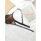 Fashion leopard bra and underwear set with black straps laid on white surface beside artwork and woven mat
