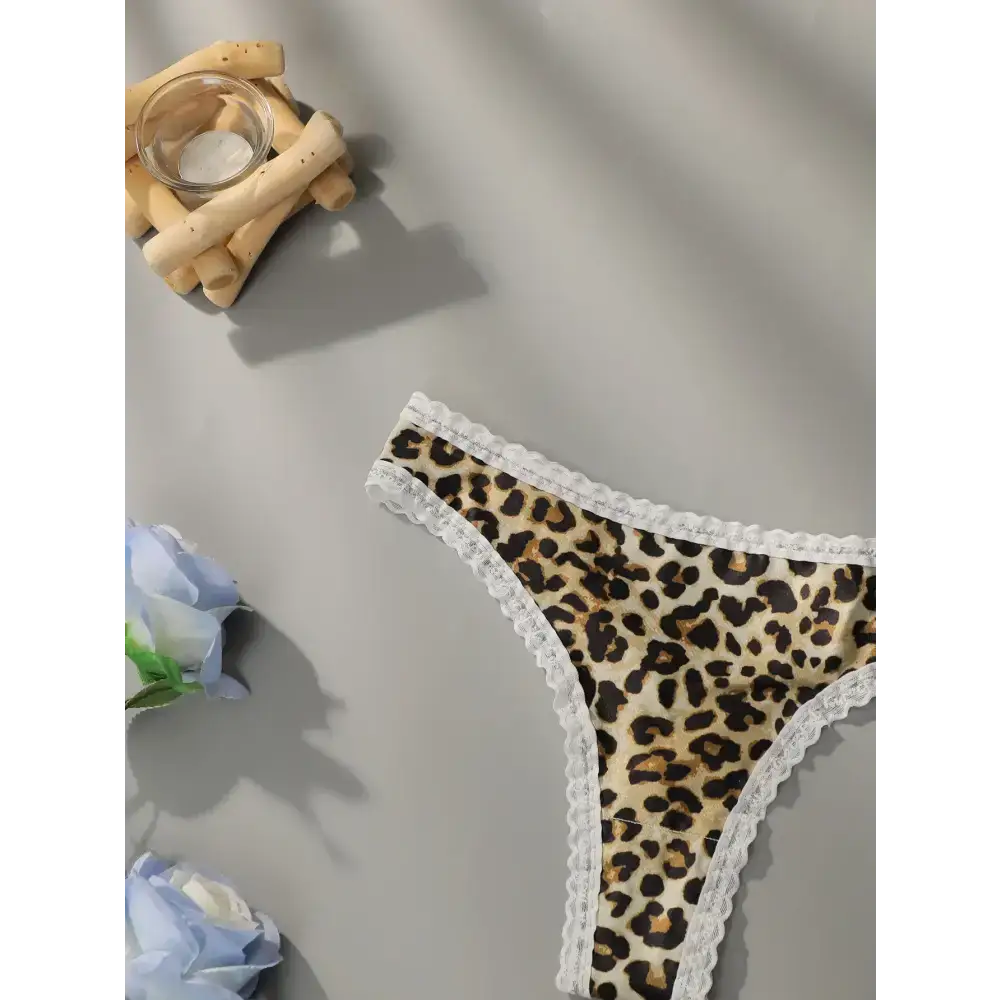 Leopard print lace underwear with white lace trim displayed on gray surface with decorative flowers