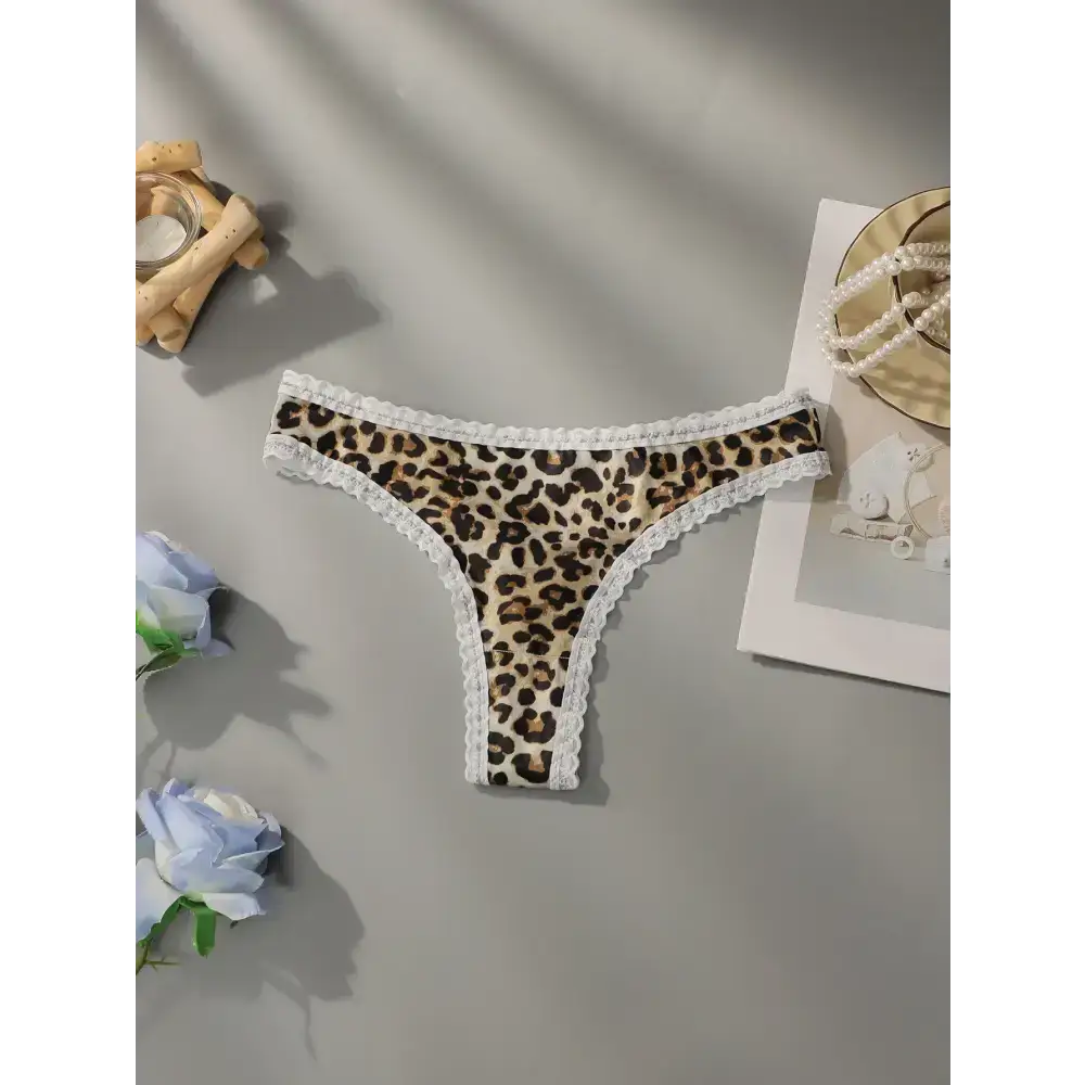 Leopard print lace underwear with white lace trim laid flat on a gray surface
