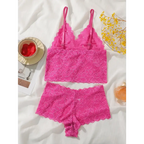 Pink lace bralette and panties set laid out on white fabric with yellow flowers nearby