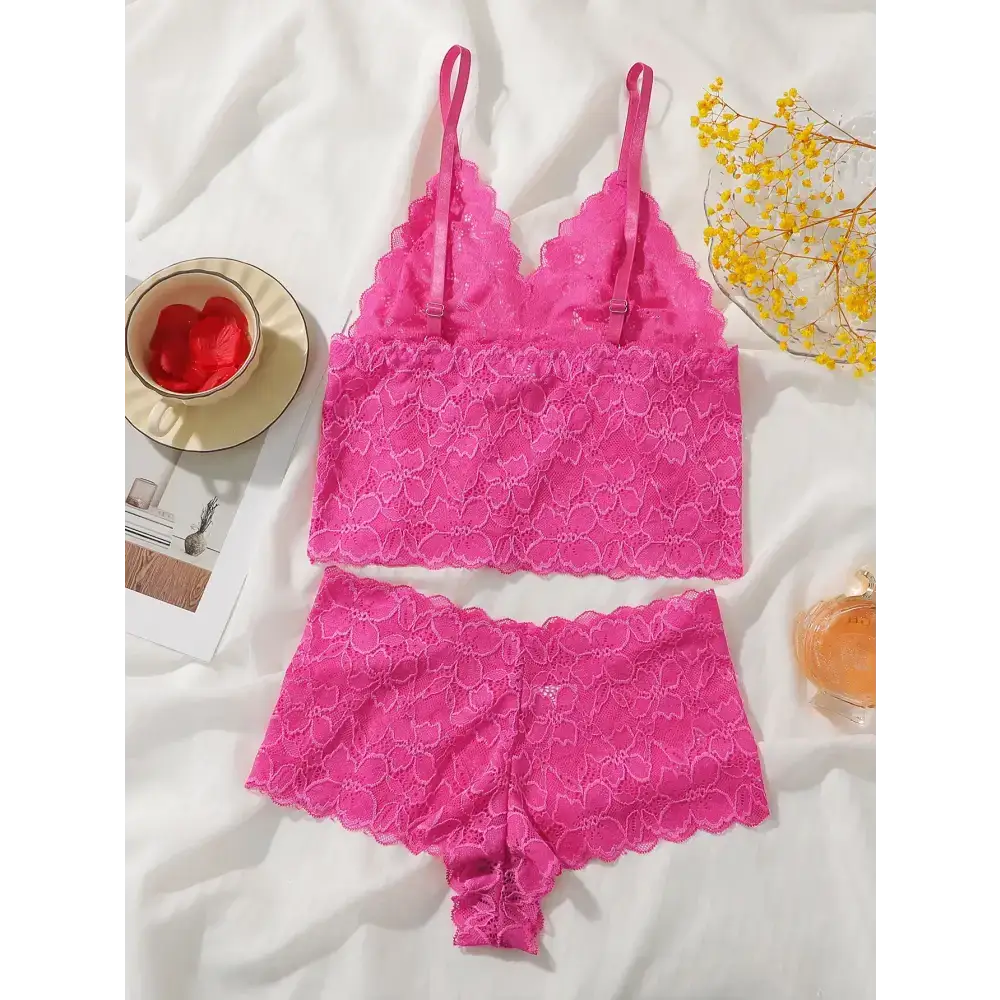Pink lace bralette and panties set laid out on white fabric with yellow flowers nearby
