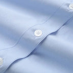 Close-up of light blue spring long sleeve office shirt with white buttons and smooth fabric