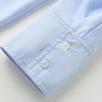 Close-up of light blue spring long sleeve office shirt cuff with white buttons and neat stitching