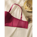 Wine red lingerie set bra with adjustable straps and hook closure laid on white fabric next to pearl necklace